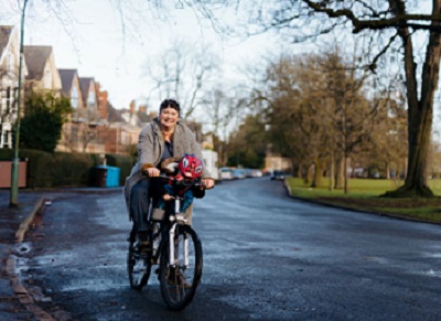 A picture of a lady on a bike with her child in the front